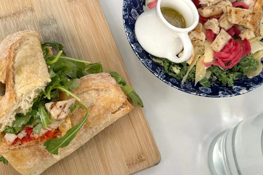 Chicken salad sandwich and greens on a wooden board