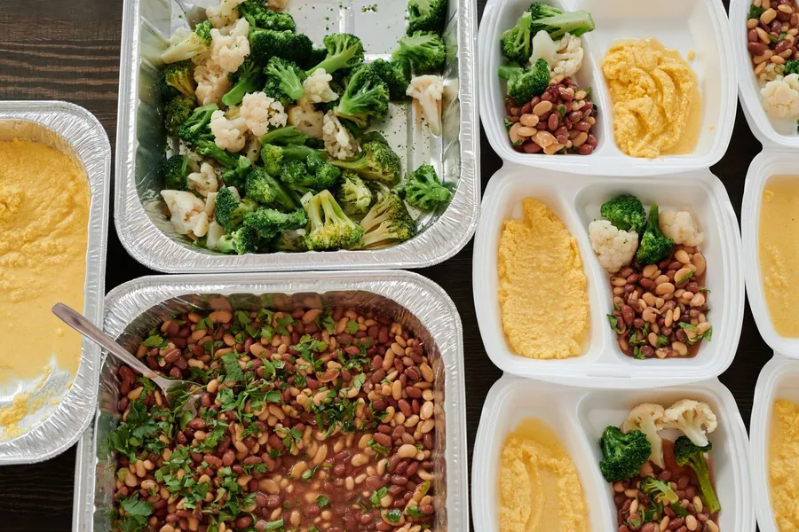 Meal prep containers with broccoli, beans, and cooked vegetables
