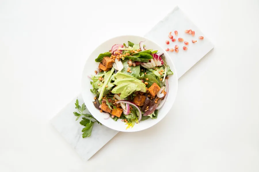 Grain bowl with vegetables and herbs on a bright kitchen table